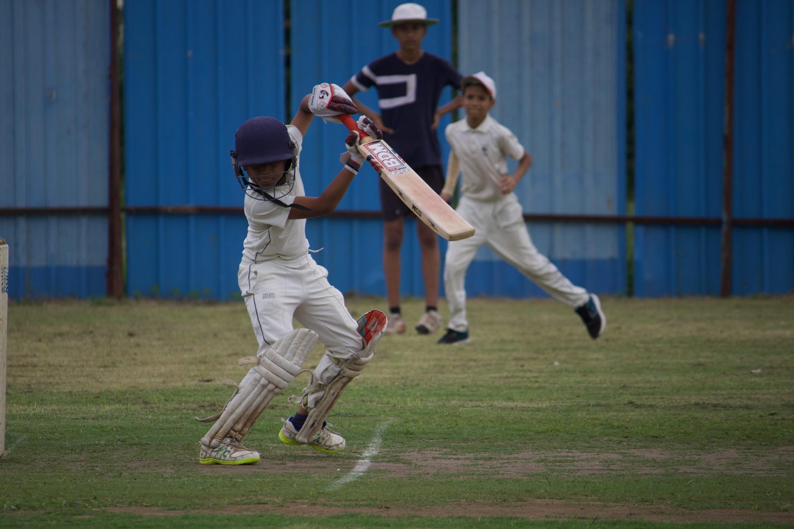 Youth cricket batting practice in white uniform